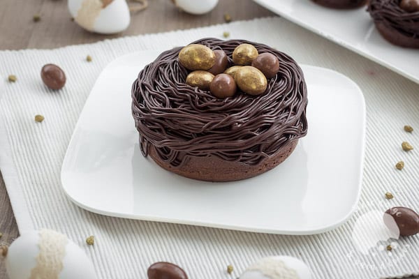 un nid de Pâques au chocolat avec des oeufs en chocolat dorés sur une assiette blanche