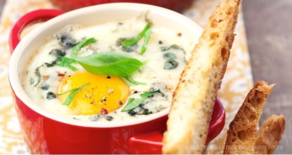 un oeuf cocotte au roquefort avec une mouillette de pain dans une casserolette rouge