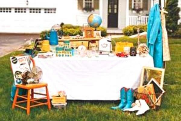 Un beau stand de vide-grenier en utilisant un vieux drap sur une table.