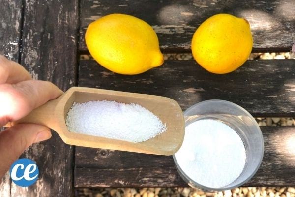 un pot de percarbonate de soude avec une cuillère en bois et deux citrons jaunes
