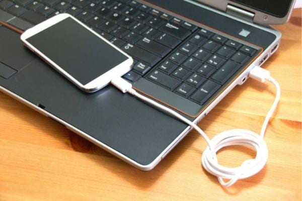 un téléphone qui est chargé en USB sur un ordinateur