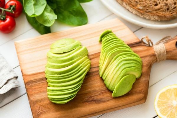 Plusieurs morceaux d'avocats découpés sur un planche en bois 