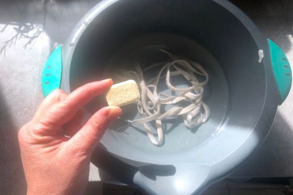 Une tablette lave-vaisselle mise dans une bassine pour blanchir les lacets