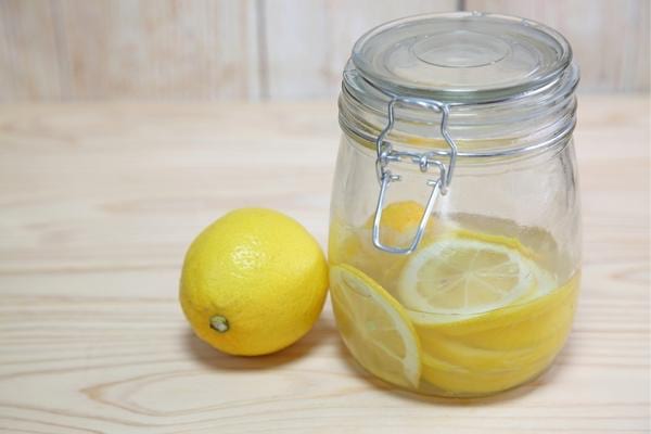 Un bocal avec un mélange de vinaigre blanc et citron pour se débarrasser des puces de parquet