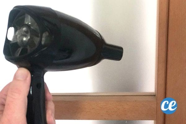 un sèche cheveux pour enlever des résidus de colle sur une fenêtre opaque
