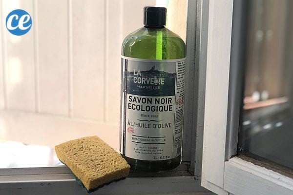 du savon noir et une éponge pour nettoyer les restes de colle sur une fenêtre