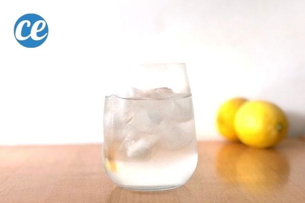 a glass of ice water on a table with two yellow lemons