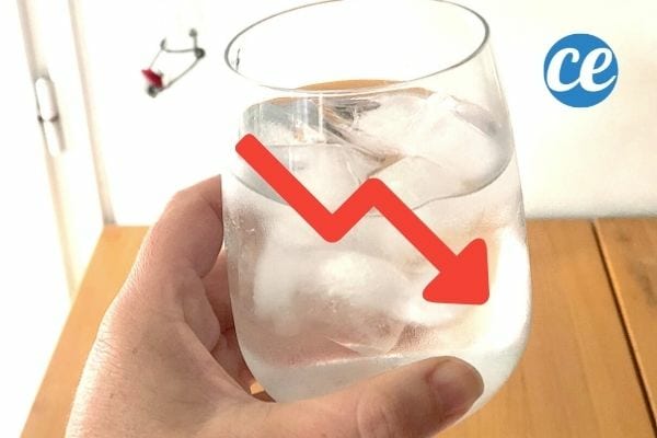 une personne boit un verre d'eau glacée avec une flèche rouge down