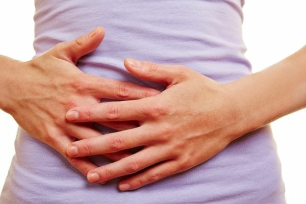 a woman holds her stomach because of digestion problem