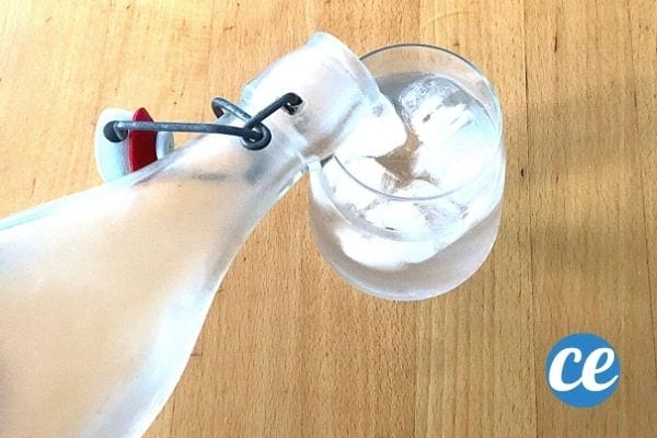 a person fills a glass of ice water with a bottle