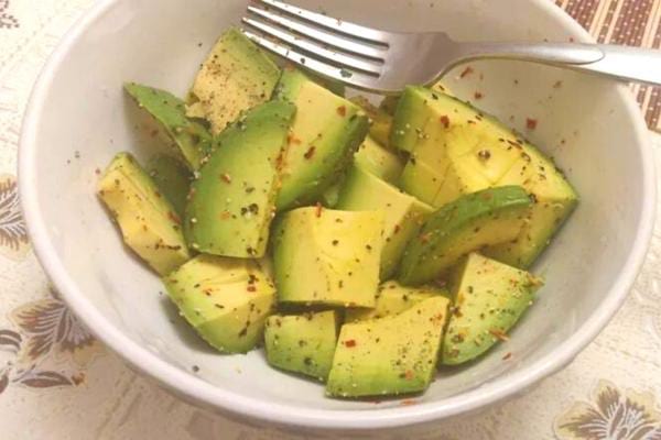 Plusieurs morceaux d'avocats avec une pincée de sel et poivre dans un bol blanc 