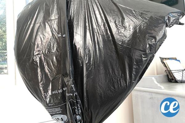 un grand sac poubelle recouvre complètement un ventilateur sur pied