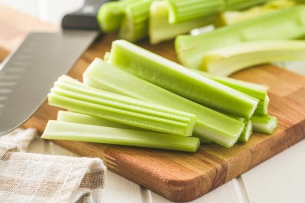 Plusieurs céleri branche découpés sur planche en bois 