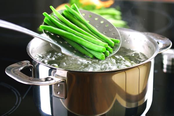 haricots verts plongés dans l'eau bouillante dans une casserole en inox pour les blanchir