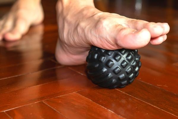 Un massage de la voute plantaire avec une balle pour soulager les douleurs au talon