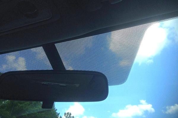 Un pare brise au soleil avec des points noirs dessus en gros plan sur une peugeot 5008