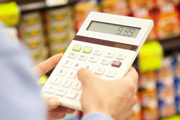 Un homme tenant une calculette dans un rayon de supermarché 