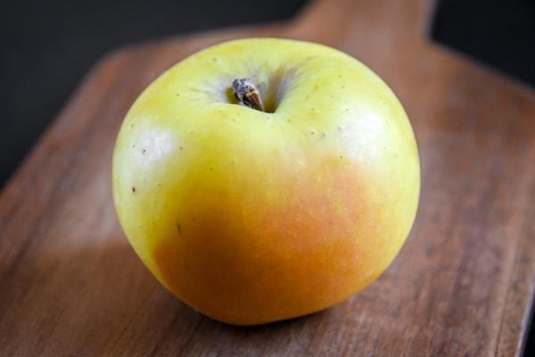 Une pomme seule sur une planche à découper 