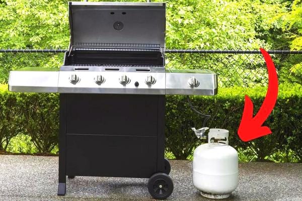 Un homme qui fait cuire de la viande sur un barbecue à gaz sans oublier de vérifier le niveau de gaz
