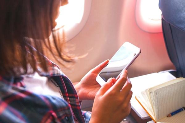 Une femme tenant un téléphone portable dans un avion créant des interférences