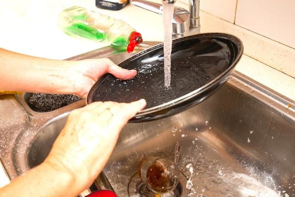 Une femme qui fait la vaisselle en laissant l'eau coulée