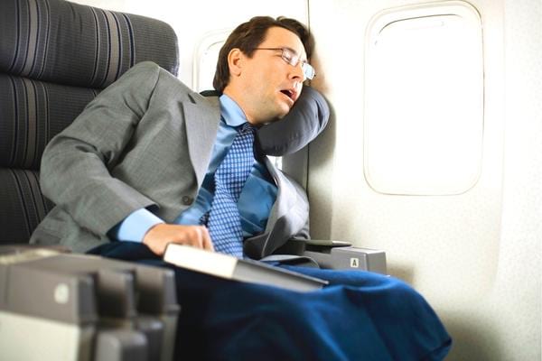 Un homme qui dort dans un avion avec une couverture pas propre