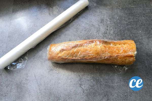 une demi baguette de pain dans du film alimentaire plastique pour être congelée.