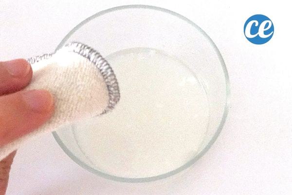 un petit récipient avec de l'eau de cuisson de riz et une personne qui trempe un coton dedans