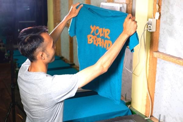 Un homme ayant un tee-shirt bleu floqué orange entre les mains