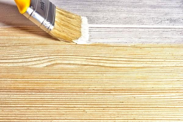 Un pinceau avec de la peinture blanche passant par-dessus du bois