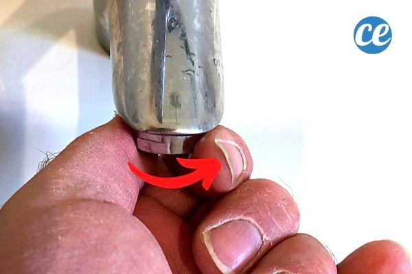 une perssone visse un mousseur sur le robinet