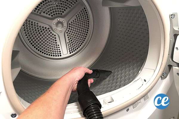 Une personne passant l'aspirateur dans le tambour d'un sèche-linge