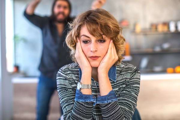 Une femme avec un air agacé avec un fond flou et un homme en arrière-plan 