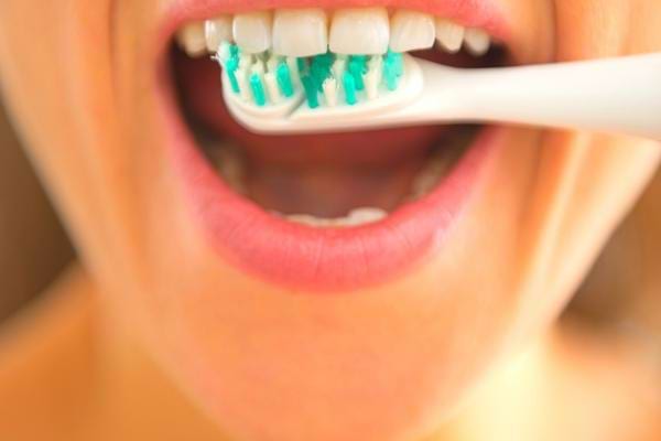 Une femme qui se brosse les dents de manière différente pour laver toutes les zones