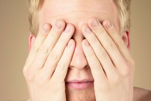 Un homme qui se cache les yeux avec ses mains