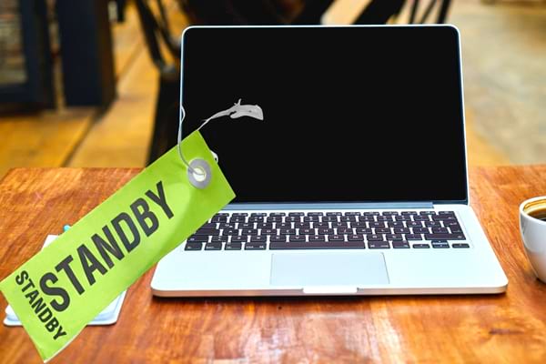 ordinateur mac en veille sur un bureau en bois