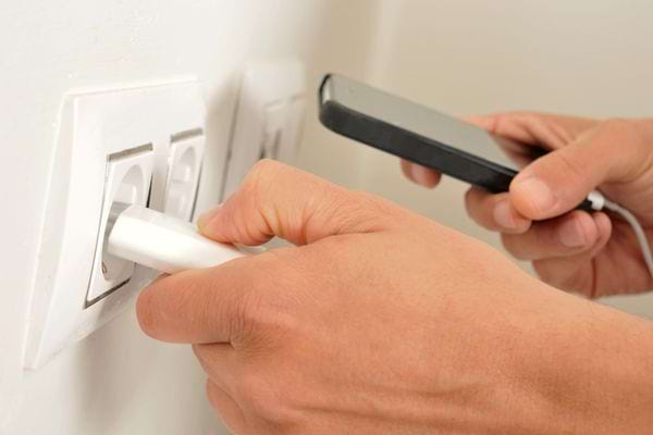Une personne débranchant un chargeur de téléphone 
