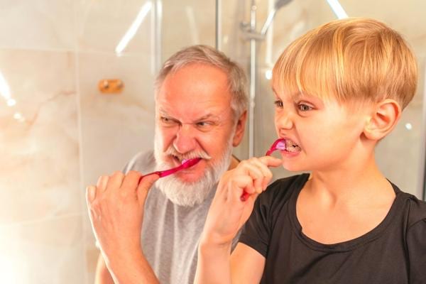 Un grand père et un garçon qui se brossent les dents de manière linéaire