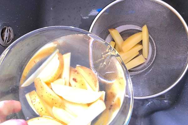 Des morceaux de pommes de terres dans une passoire 