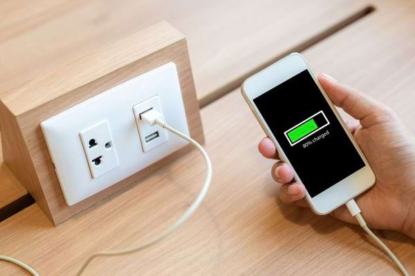 Un téléphone blanc qui charge dans les mains d'une personne