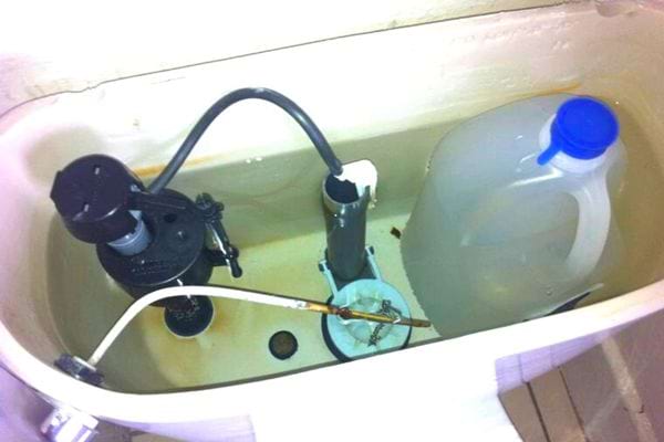 Une bouteille d’eau dans le réservoir des toilettes