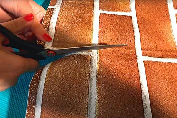 Une femme découpant l'autocollant pour la fausse cheminée