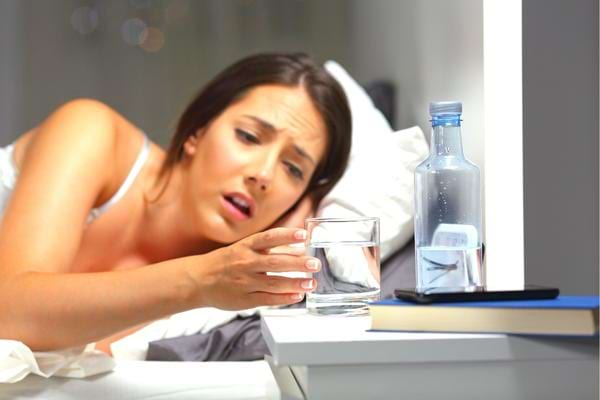 Une femme qui boit un verre d'eau pour se rendormir