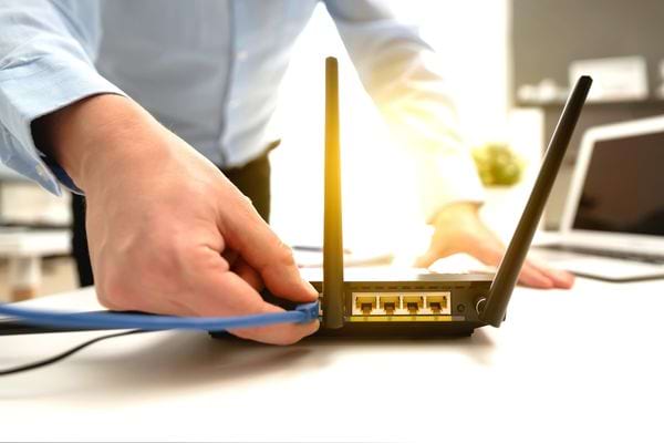 Un monsieur branchant un fil bleu sur une box 