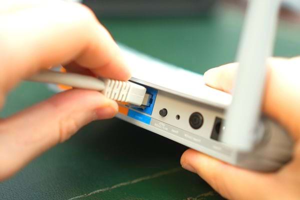Une personne branchant un fil blanc sur une box 
