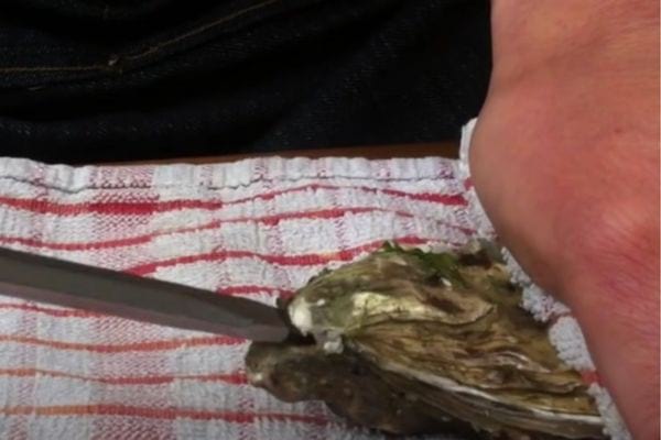 Une personne ouvrant des huîtres avec un tournevis