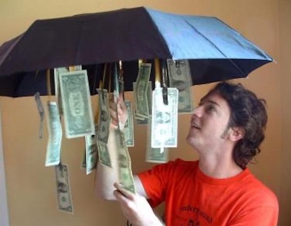 Un homme tenant un parapluie avec plusieurs billets Américains suspendues dessus