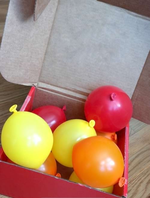 Un carton ouvert remplie de ballons jaunes et rouges