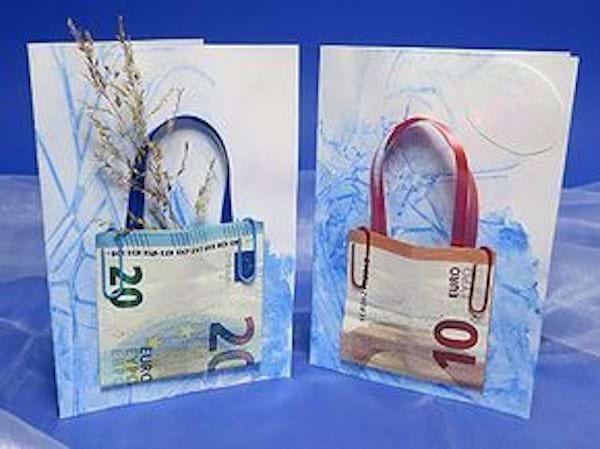 Des billets en origami qui sont faits en forme de mini sacs collés sur des feuilles 