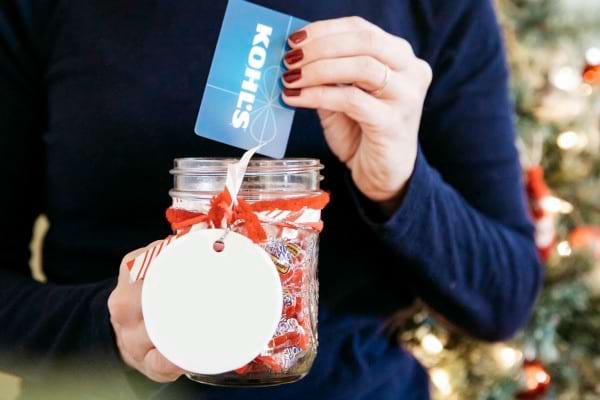 Une femme tenant un bocal de friandise ouvert avec une carte bleue 